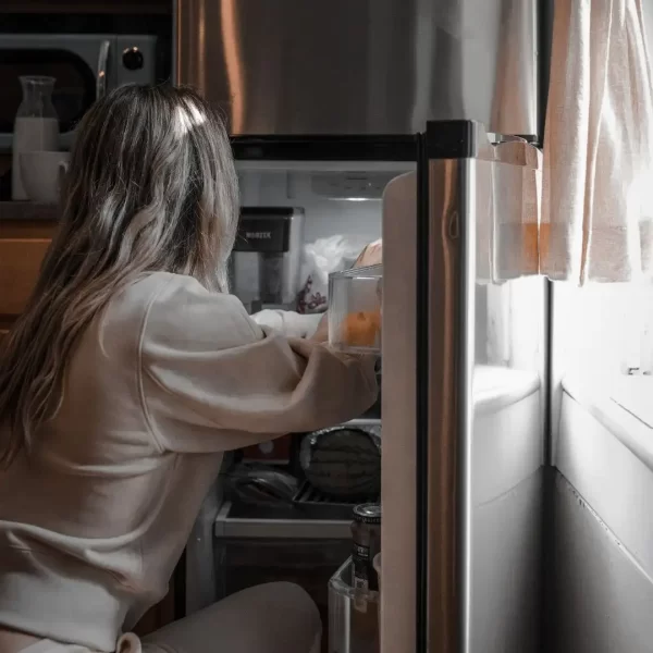 Persona comiendo por ansiedad frente a la nevera abierta